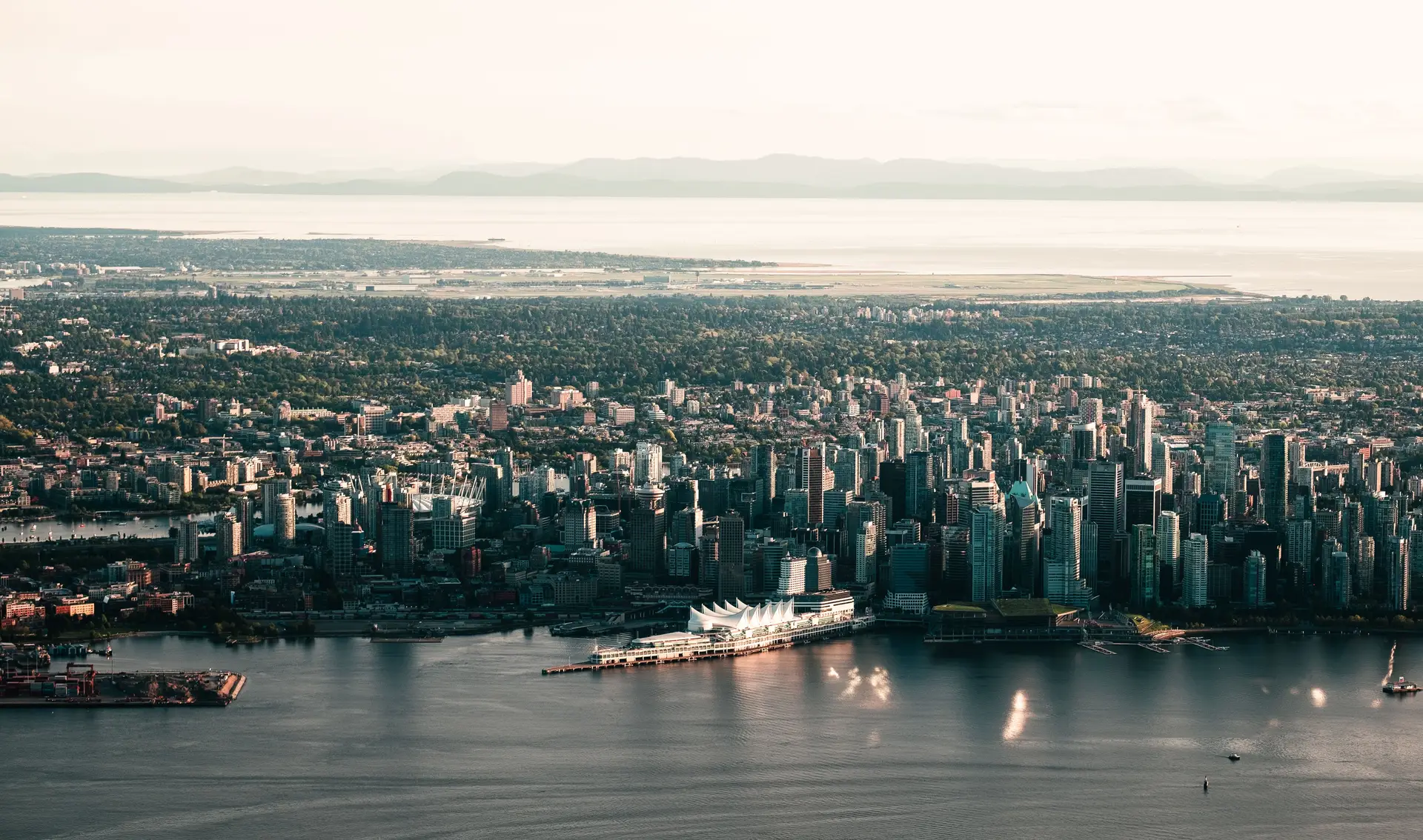 Aerial panorama of coastal Vancouver waterfront and snow-dusted coastal mountain range